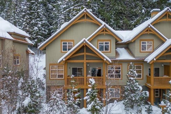 Snow-covered Whistler townhome rental surrounded by evergreen trees.